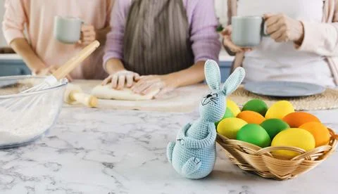 Basket with colorful eggs and Easter bunny on kitchen table during preparatio Stock Photos