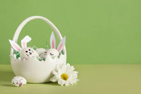 Basket of creative Easter eggs with flowers on green background Stock Photos