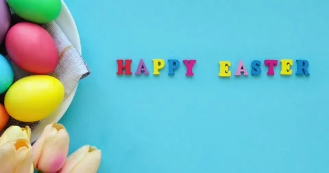Basket with easter colored eggs, tulips and  inscription happy easter Stock Footage 235773552