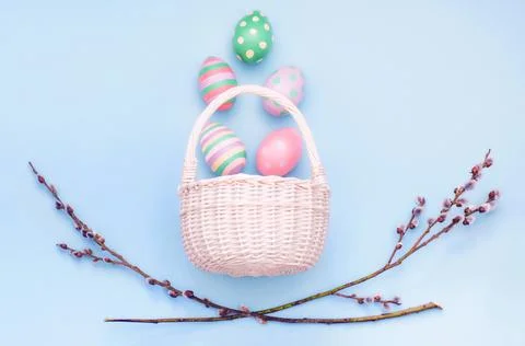 Basket with Easter eggs and branches of flowering willow on a blue background Stock Photos