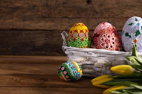 A basket with Easter eggs on a background of boards and tulips lying next to it. Stock-Fotos