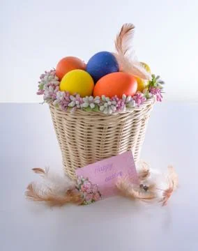 Basket with easter eggs, feathers and card with wishes Stock Photos