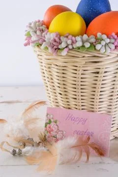 Basket with easter eggs, feathers, ladybug and card with wishes Stock Photos