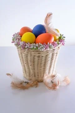Basket with easter eggs with feathers on white table Stock Photos