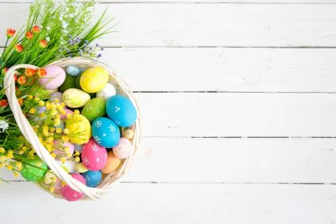 Basket with easter eggs on rustic wooden table. Top view. Stock Photos