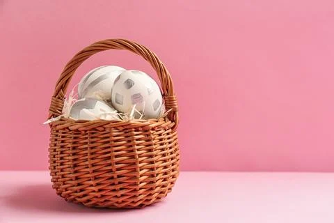 Basket of Easter eggs on table against color background. Space for text Foto stock