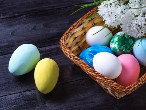 Basket with Easter eggs, white flowers on a dark wooden background Stock Photos
