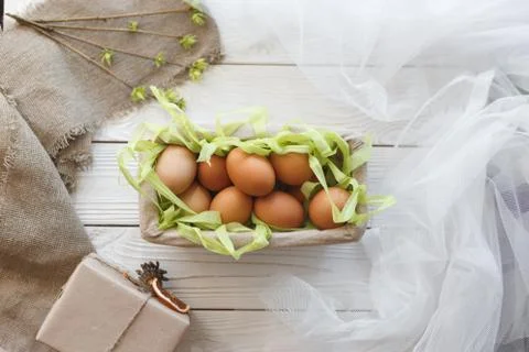 Basket with eggs and spring decor on a white wooden background Stock Photos