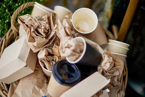 Basket filled with garbage with disposable tableware, top view. Фото