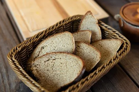 Basket filled with slices of bread. The basket is woven and sits on a wooden  Stock Photos