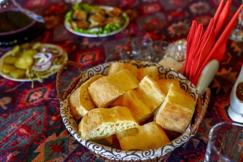 Basket of fresh bread on colorful patterned table ready to share Stock Photos