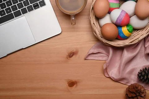 Basket full of Easter eggs and laptop computer on wooden background. Easter Foto stock