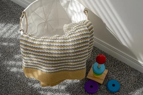 A basket full of knitted items, including a striped blanket and a teddy bear Foto stock