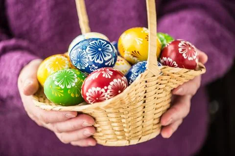 Basket full of multicolored easter eggs in hands pensioner woman Stock Photos