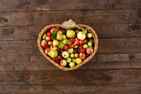 Basket full of ripe apples and pears on a wooden background. View from above. Stock Photos