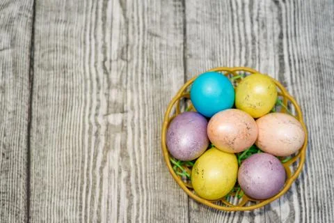 A basket with many multi colored easter eggs on the wooden background. Stock Photos