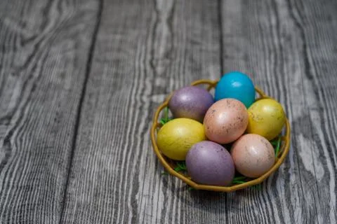 A basket with many multi colored easter eggs on the wooden background. Stock Photos