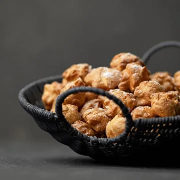 Basket of mini eclairs on gray background. Delicate French profiteroles dessert Stock Photos