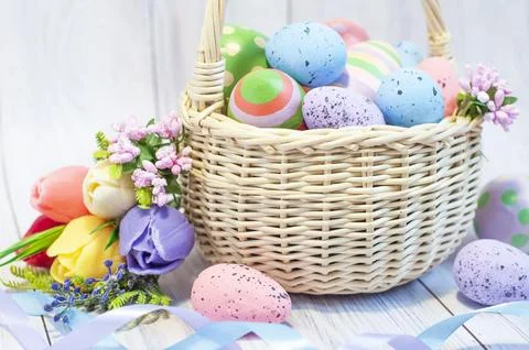Basket with painted Easter eggs and spring flowers on a light wooden background Stock Photos