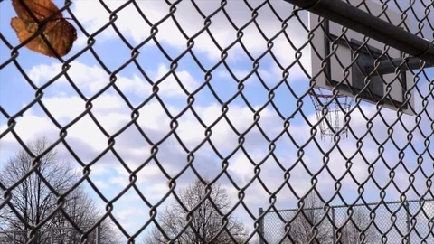 Basket Ring view focused through metal grey fence foreground and leaves. Stock Footage 98573618