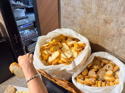 Basket with sliced bread covered in plastic bags at breakfast buffet. Hotel d Stock Photos