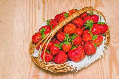 Basket of strawberries on the table surface. Stock Photos
