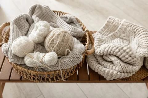Basket with threads for knitting on a wooden bench in the interior of the room. Stock Photos