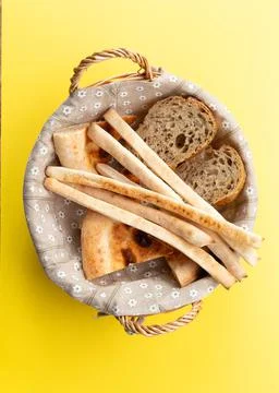 Basket with various types of bread. On a yellow background. Stock Photos