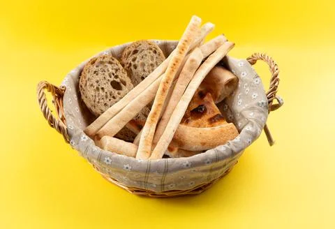 Basket with various types of bread. On a yellow background. Stock Photos