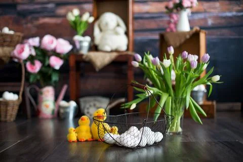 Basket with white easter eggs on the foreground and a vase with flowers, duck Stock Photos