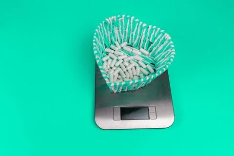 Basket with white tablets stands on kitchen scales Stock Photos