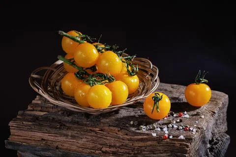 Basket of yellow cherry tomatoes on rustic wood with scattered salt Stock Photos