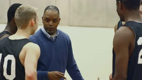 A basketball coach talking to his players in a huddle before a game Stock Footage