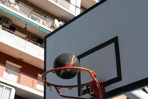 Basketball falling through hoop in urban setting Stock Photos