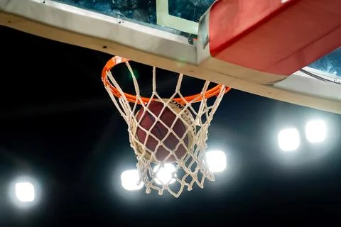 Basketball going through the net during a game in a large arena Foto stock
