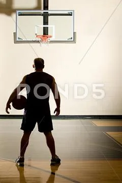 Basketball player alone in basketball court Stock Photos