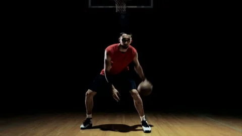 A basketball player dribbles between his legs. Video stock 83607891
