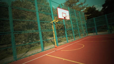 A basketball player energetically shooting hoops on a sunny outdoor court during Stock Footage 301463450