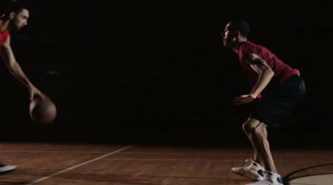 A basketball player goes one on one against a defender and then slam dunks Stock Footage 33993920