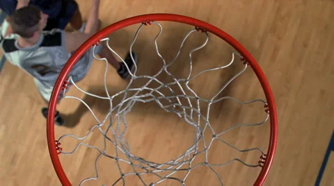 Basketball player jumping to drop ball through net, viewed in slow motion from Stock Footage