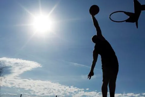 Basketball player mid air slam dunk silhouette Stock Photos
