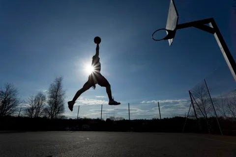 Basketball player mid air slam dunk silhouette Stock Photos