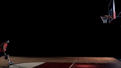 A basketball player runs up and does a trick dunk by himself Video stock 83608246