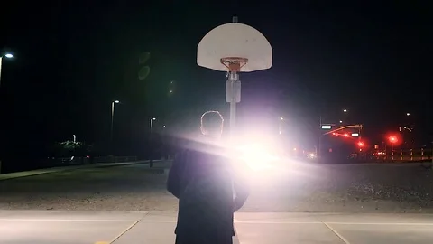 Basketball Player Shoots Free Throws Outdoors against Traffic Lights Stock Footage 104644594