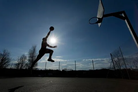Basketball player silhouette taking off to slam dunk Stock Photos