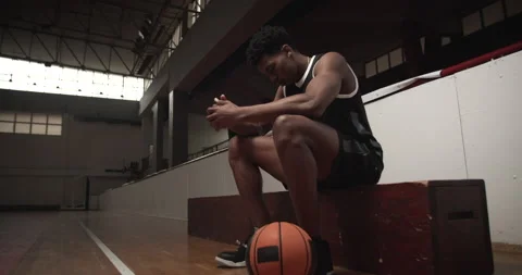 Basketball player sitting on a bench, serious and concentrated. Stock Footage 144856565