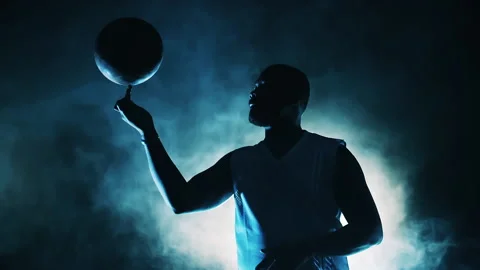 Basketball player is spinning a ball on his finger in clouds of smoke Stock Footage