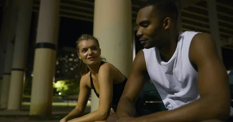 Basketball players high-fiving while sitting on a bench at night Stock Footage 112017108