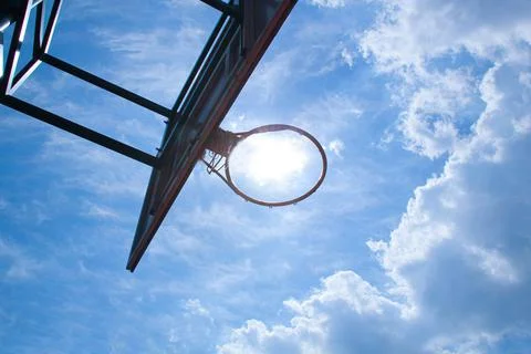 Basketball ring on the background a blue sky with white clouds and bright sun Stock Photos