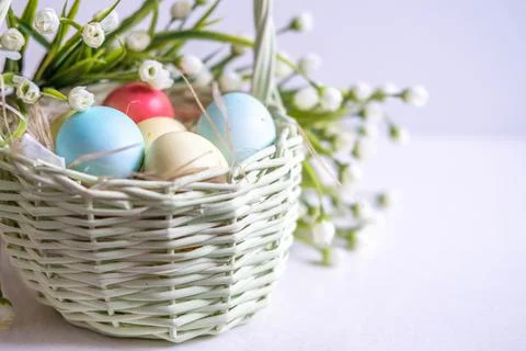 Baskets with Easter colored eggs on a white wooden table surrounded by delicate Foto stock